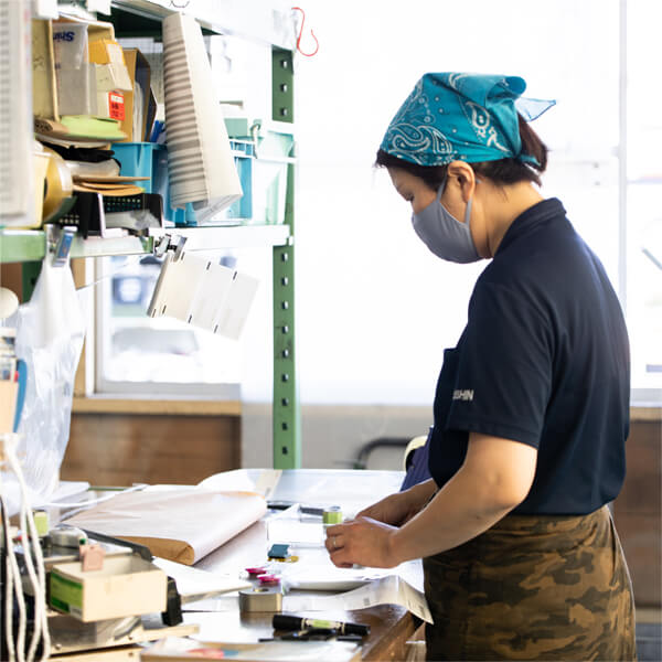 自動車倉庫内で小物部品のパック詰め